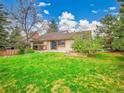 A spacious backyard featuring a lush lawn, mature trees, and a cozy patio area at 8546 E Mineral Cir, Centennial, CO 80112