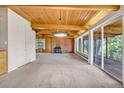 Open living room with exposed wood ceiling beams, a cozy brick fireplace, and access to an outdoor deck at 1 Lindenwood Dr, Littleton, CO 80120