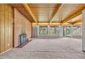 Spacious living room with exposed wood beam ceiling, brick fireplace, and large windows overlooking the backyard at 1 Lindenwood Dr, Littleton, CO 80120