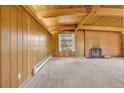 Cozy living room featuring exposed wood beam ceiling, brick fireplace, and wood paneled walls at 1 Lindenwood Dr, Littleton, CO 80120