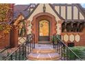 Close-up of the arched front door with brick surround and stone steps with wrought iron railings at 1930 E 8Th Ave, Denver, CO 80206