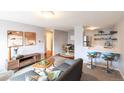 Bright living room with a cozy sectional sofa, decorative artwork, and a breakfast bar with seating at 1260 York St # 204, Denver, CO 80206