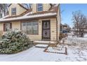 Close up of the home's entry, with a secure storm door, and snowy landscaping at 1390 W Gill Pl, Denver, CO 80223