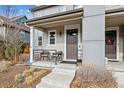 Inviting covered front porch with seating and a stylish entrance door at 8157 E 53Rd Dr, Denver, CO 80238