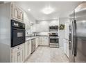 Bright kitchen featuring white cabinets, stainless steel appliances, and tiled flooring at 6410 Independence Way, Arvada, CO 80004