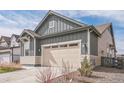 Two-car garage home with vertical blue siding and beige accents for a modern look at 6311 Stable View St, Castle Pines, CO 80108