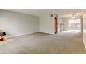 Spacious living room with neutral carpet, natural light, and convenient access to in-unit laundry and kitchen at 3855 S Monaco St # 177, Denver, CO 80237