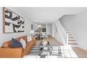 Open-concept living area with modern furnishings, including a sleek sofa, contemporary art, and a staircase to the upper level at 1818 S Quebec Way # 2-3, Denver, CO 80231