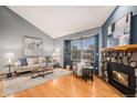 Bright living room features a stone fireplace, hardwood floors, and a large window at 8304 S Upham Way, Littleton, CO 80128