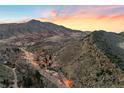 Scenic aerial view captures the landscape and town below a mountain range under a vibrant sunset sky at 14412 Pansy Loop, Morrison, CO 80465