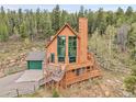 An eye-level exterior elevation view showcases a home featuring a wrap-around deck, perfect for enjoying the serene natural surroundings at 30382 Marys Dr, Conifer, CO 80433