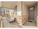 Inviting covered front porch with stone accents and comfortable seating, perfect for relaxing outdoors at 45831 Silverdrop Ave, Bennett, CO 80102