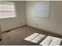 Sunlit bedroom with neutral carpet, two windows, fresh paint, and electrical outlets at 5543 Victor St, Denver, CO 80239