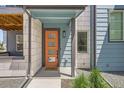 Inviting front entrance with a modern orange door and stylish exterior lighting at 6791 Navajo Ct, Denver, CO 80221