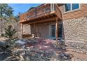 Charming home exterior with a wooden deck, stone accents, a brick patio, and natural landscaping at 27231 Log Trl, Conifer, CO 80433