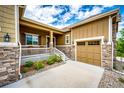 Charming covered front porch and two car garage on this well-maintained home with a stone facade and tasteful landscaping at 3855 Old Oaks St, Castle Rock, CO 80104