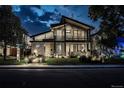 Night view of a stylish modern home with a balcony, manicured lawn, and illuminated walkway and landscaping at 1175 S Jackson St, Denver, CO 80210
