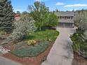 Aerial view of gray two-story home with mature trees, landscaped lawn, and a spacious driveway at 7605 E Windlawn Way, Parker, CO 80134