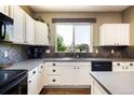 Well-lit kitchen features white cabinetry, modern appliances, and a window with a pleasant view at 2214 E 101St Ave, Thornton, CO 80229