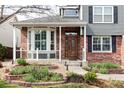 Inviting covered front porch with decorative brickwork and lush landscaping at 674 Huntington Dr, Highlands Ranch, CO 80126