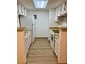 Well-lit kitchen with white cabinets, modern appliances, and laminate wood floors at 4400 S Quebec St # 102R, Denver, CO 80237