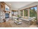 Cozy living room featuring a stone fireplace, large windows with lush views, and stylish neutral furnishings at 29011 Upper Moss Rock Rd, Golden, CO 80401