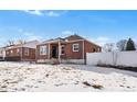 Cute brick ranch home with a white picket fence and snow covered yard at 501 S Dale Ct, Denver, CO 80219