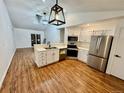 Modern kitchen featuring stainless steel appliances, white cabinetry, and wood flooring, offering a stylish design at 4036 S Himalaya Cir, Aurora, CO 80013
