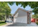 Side view of a two-car garage attached to a home with a light gray exterior and brick accents at 647 Florence Ave, Firestone, CO 80520