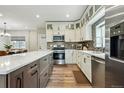 Bright kitchen features an island, stainless appliances, white cabinetry and wood-look floors at 3165 W 63Rd Ave, Denver, CO 80221