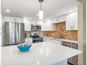 Modern kitchen with stainless steel appliances, white cabinetry, backsplash and a large island with white countertops at 13961 E Marina Dr # 414, Aurora, CO 80014