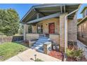 Charming brick home featuring a covered front porch with classic architectural details and landscaping at 2854 Eliot St, Denver, CO 80211
