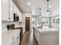 Bright kitchen featuring white cabinets, stainless appliances, a spacious island, and wood grain flooring at 2267 Peregrine Dr, Brighton, CO 80601