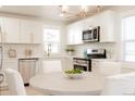 Bright kitchen features white cabinets, stainless appliances, quartz counters, and a stylish gold light fixture at 3728 W Exposition Ave, Denver, CO 80219
