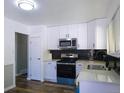Modern kitchen featuring sleek, white cabinets, stainless steel appliances, and a dark backsplash at 11937 Claude Ct, Northglenn, CO 80233