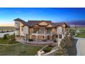 Custom home featuring a turret, multiple balconies, and lush landscaping at 12565 Picadilly Rd, Commerce City, CO 80022