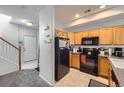 Efficient kitchen featuring wood cabinets and black appliances with convenient access to the staircase at 2235 Coronado Pkwy # A, Denver, CO 80229