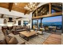 Open-concept living space with rustic beams, large windows with outdoor views, and comfortable seating areas at 3148 Keep Dr, Sedalia, CO 80135
