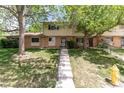 Inviting two-story townhome features a well-manicured lawn, brick facade, and mature trees at 1202 S Troy St, Aurora, CO 80012