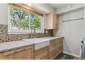 Bright laundry area features a farmhouse sink, mosaic backsplash, gray cabinets, and view to the backyard at 1202 S Troy St, Aurora, CO 80012