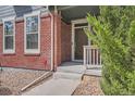 Close-up view of a home's entry featuring a brick facade, front door, and small landscaping at 14732 E Poundstone Dr, Aurora, CO 80015