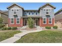 Inviting townhouse exterior featuring a walkway and green lawn, enhanced by the brick facade and blue siding at 14732 E Poundstone Dr, Aurora, CO 80015
