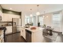 Modern kitchen with stainless steel appliances, a center island, pendant lighting, and an open view of the dining area at 14732 E Poundstone Dr, Aurora, CO 80015
