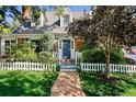 Inviting home entrance with a brick walkway, lush greenery, white picket fence, and a blue door at 7001 S Newport St, Centennial, CO 80112