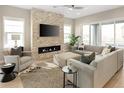 Bright living room featuring a stone fireplace, sleek TV, and comfortable seating area at 6530 Barnstead Dr, Castle Pines, CO 80108