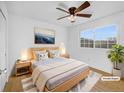 A bedroom with a ceiling fan, large window, and light wood furniture creates a serene space at 13058 Monaco Way, Thornton, CO 80602