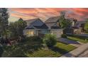 Inviting home with manicured lawn, mature trees, and a colorful sunset backdrop at 15926 Butterwort Cir, Parker, CO 80134
