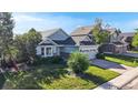 Charming light blue home featuring a manicured lawn, mature trees and a two-car garage at 15926 Butterwort Cir, Parker, CO 80134