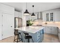 A bright kitchen with a large island, pendant lighting, white cabinetry, and stainless steel appliances at 25362 E Indore Dr, Aurora, CO 80016