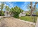Well-maintained gray home featuring a gravel driveway, lush lawn, and mature landscaping at 113 E Saint Clair Ave, Longmont, CO 80504